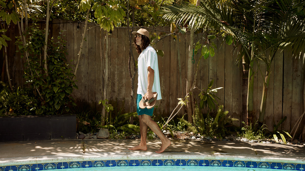 Cobian Model holding ARV 2 Sage while walking alongside a pool in a tropical backyard #color_sage