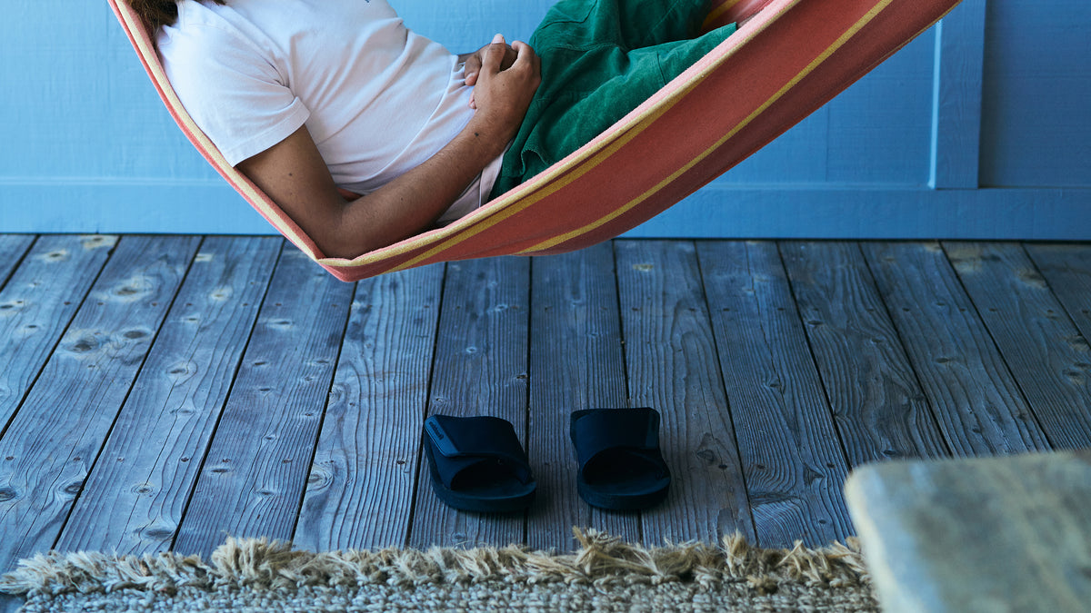 Cobian Model laying in hammock with ARV 2 Slide Black on wood floor below #color_black