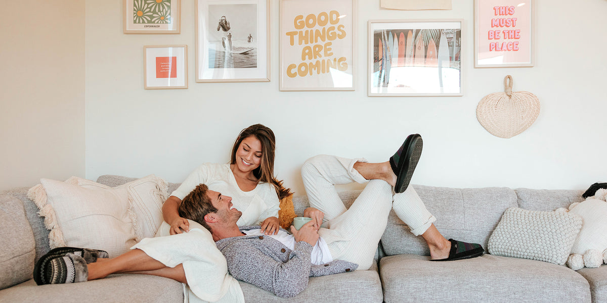 Couple relaxing on a cozy living room sofa with pastel decor and framed wall art